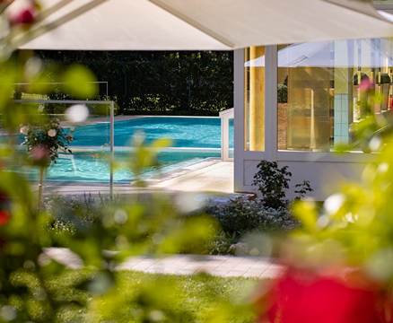 Außenpool mit Sonnenschirm und Gebüsch