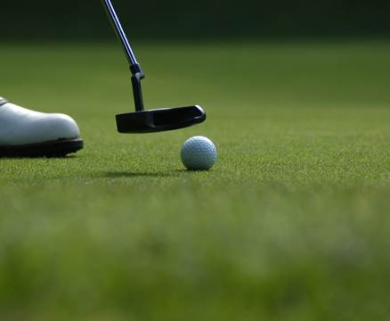 Golfball & Golfschläger auf grüner Wiese